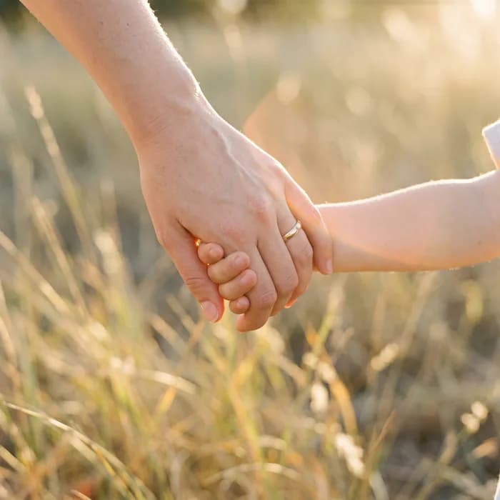 La mano de una mamá y la de su hijo, entrelazadas