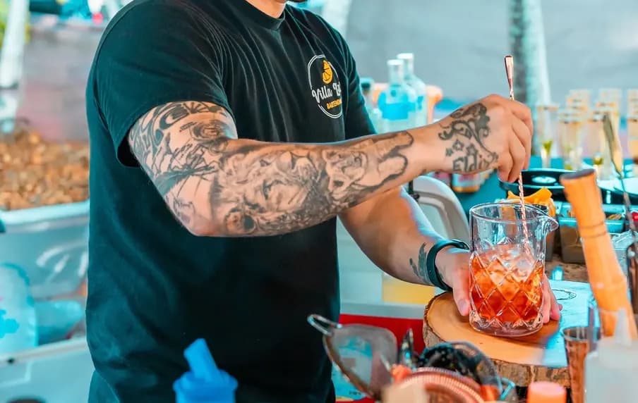 Un bartender de Villa Bar preparando un cóctel bajo un techo de palma.
